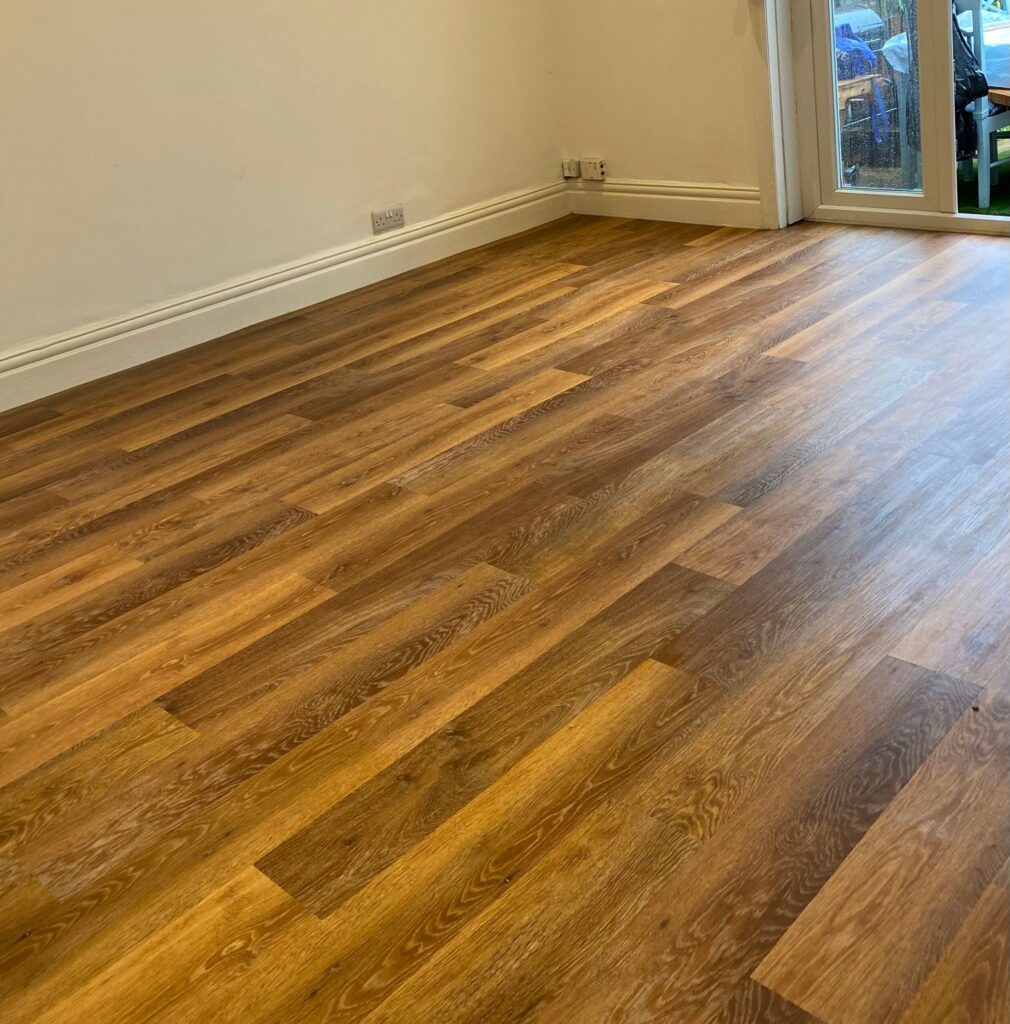 Room with dark wood-effect flooring and natural light from a glass door.